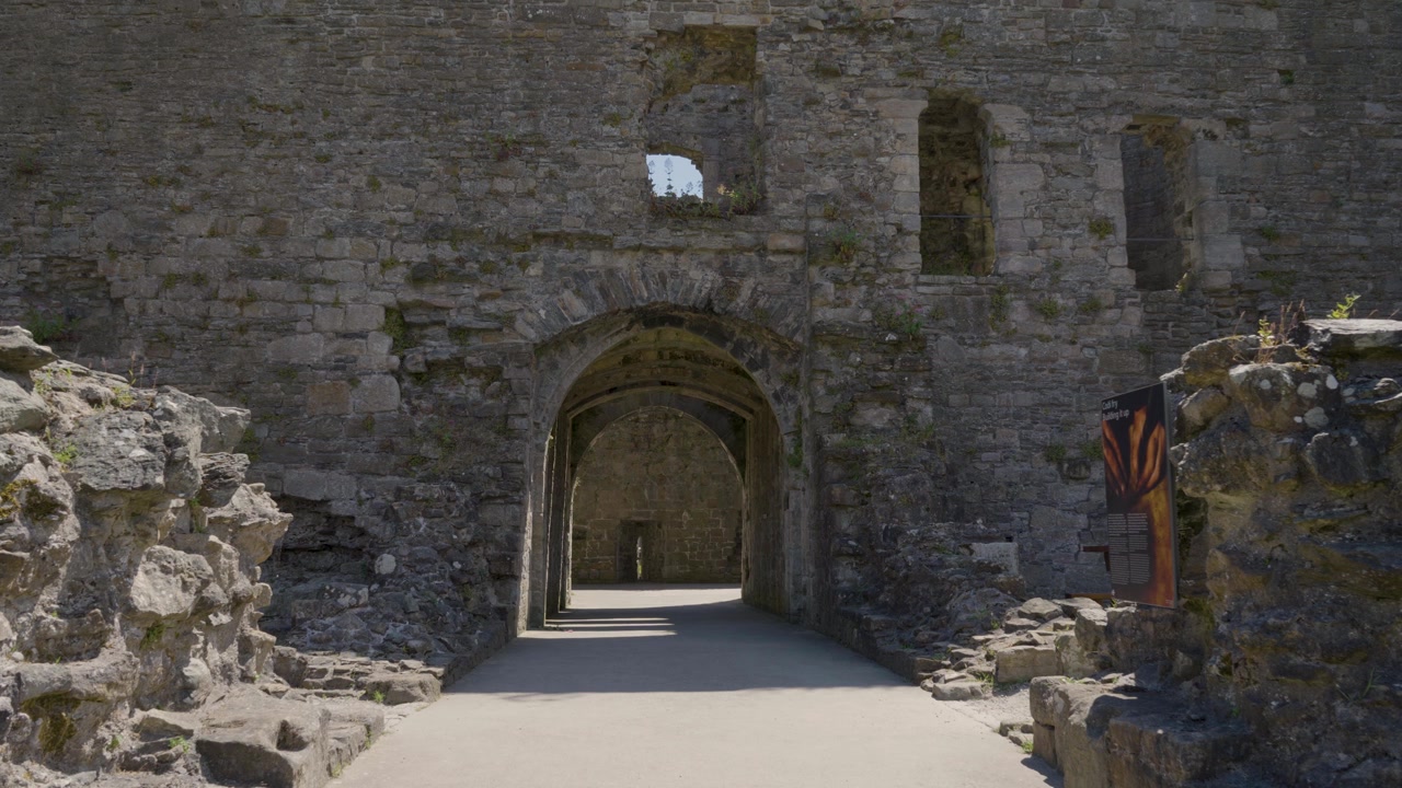 Immagini fisse che si concentrano sulle aspre mura interne del Castello di Beaumaris, mostrando singoli blocchi di pietra, texture irregolari e segni di agenti atmosferici che rivelano l'età della struttura medievale