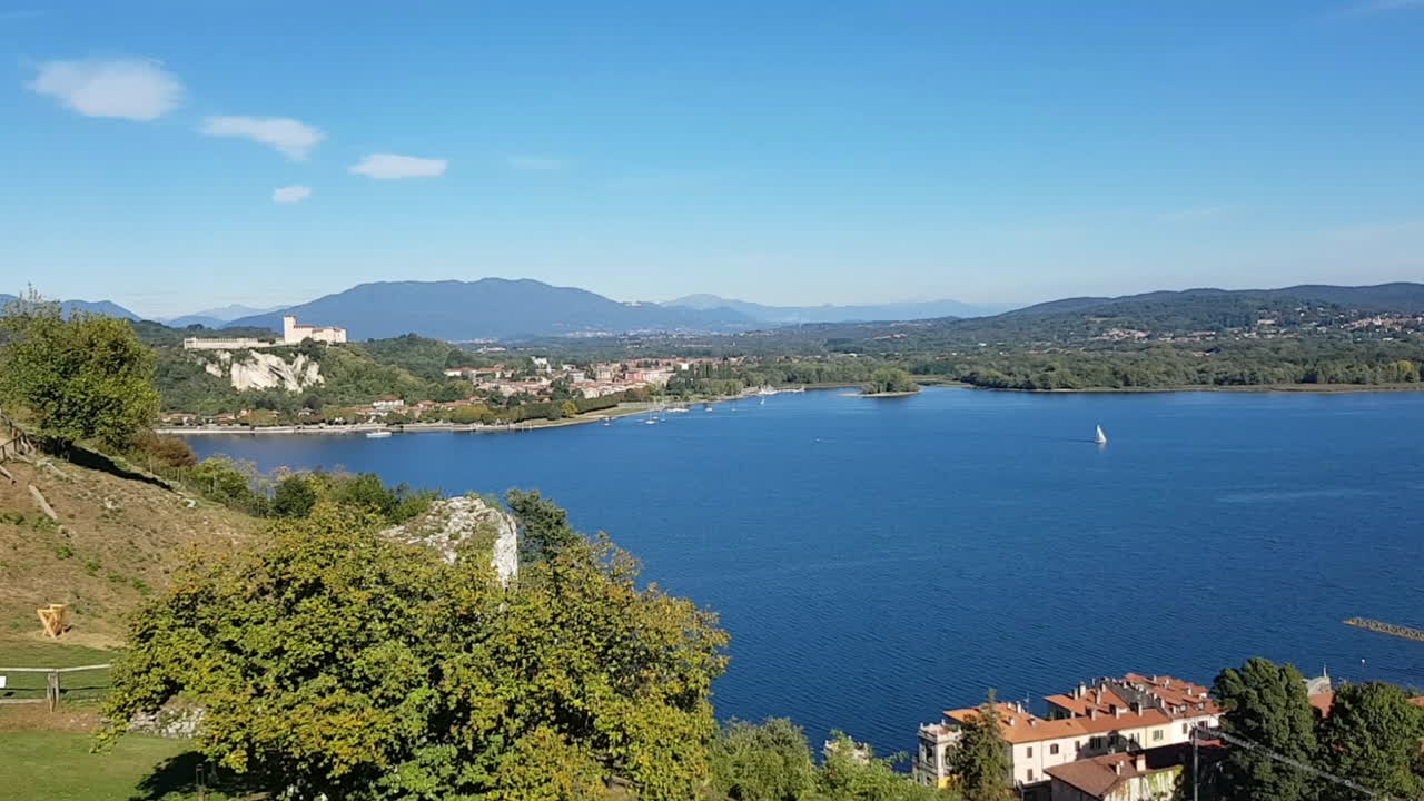 로카 오브 아로나 (rocca di arona) 에서 볼 수 있는 마조레 호수 (lago maggiore) 의 공중 풍경, 멀리서 볼 수 있는 앙제라 성 (castello di angera) 과 선박 항해