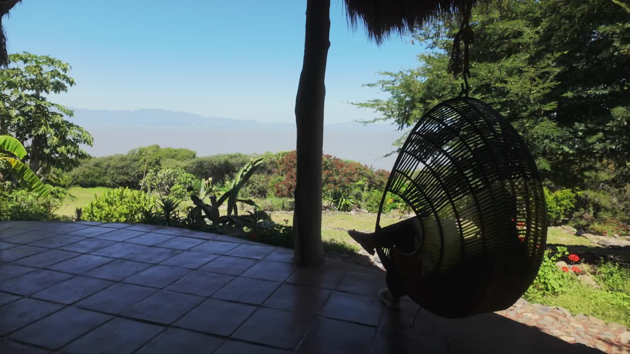 Woman relaxing at mountain retreat with scenic outdoor patio and green forest view, ideal for peaceful getaways as she enjoys her book