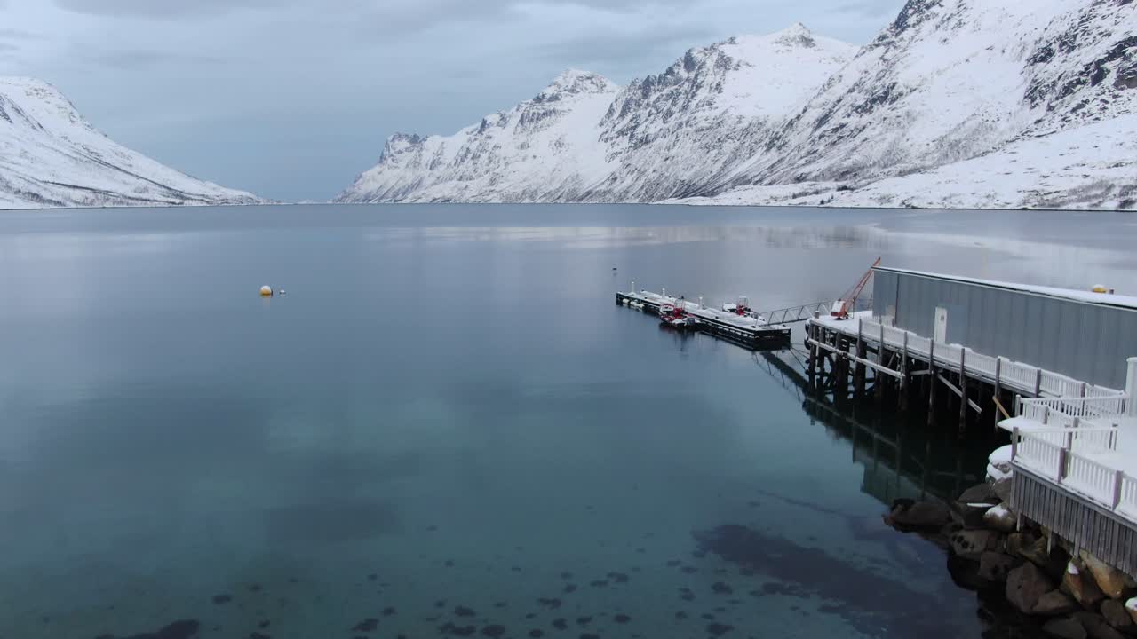 노르웨이의  눈이 쌓인 산으로 둘러싸인 비석 해변과 피오르드를 보여주는 겨울의 수직 엘리베이터에서 트롬소 지역의 드론 뷰