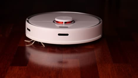 smart robot vacuum cleaner with lidar on wood floor. robot vacuum cleaner performs automatic cleaning of the apartment. slow motion 100 fps. ungraded video