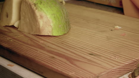 close-up macro: raw turnip is cut into pieces on wood chopping block