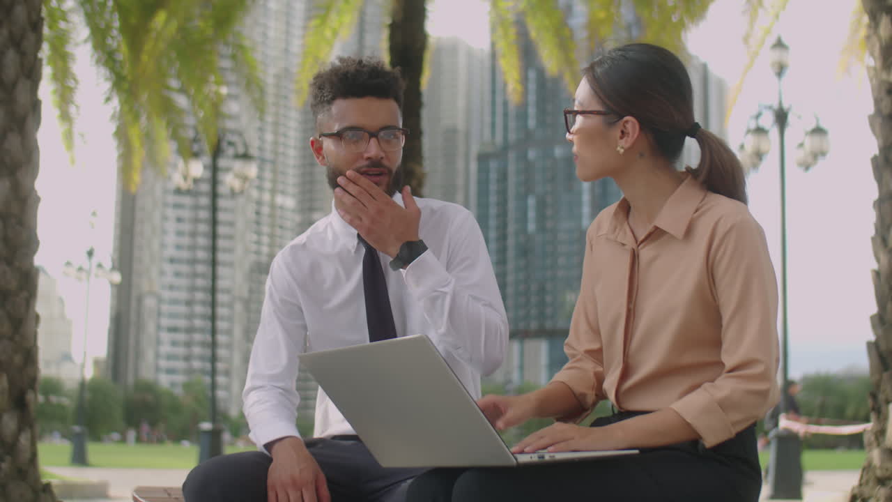 Colleagues Using Laptop and Speaking Outdoors in City