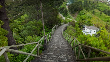 POV descent down a scenic stone staircase in São Vicente, Madeira, surrounded by lush greenery and mountain landscape on a cloudy day