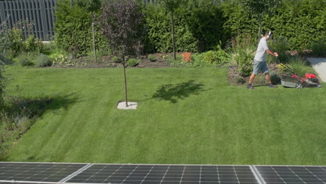 a man mows the lawn in the courtyard of the house, listens to music on headphones.