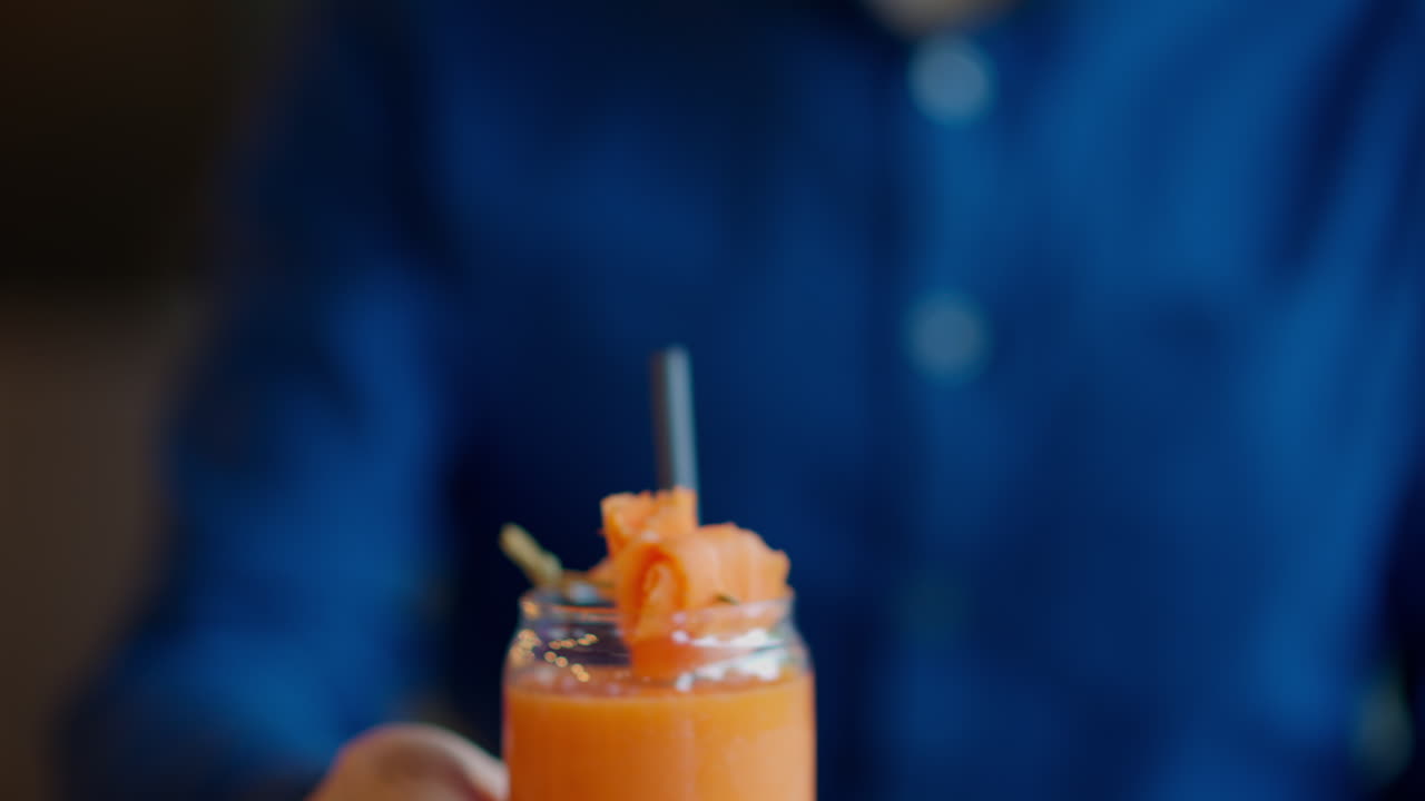 Uomo che beve succo di carota con una cannuccia in un ristorante