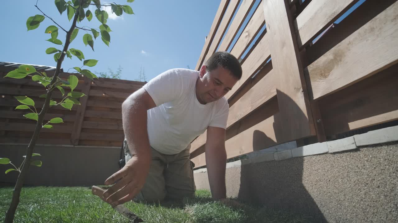 jardinero colocando césped en el patio privado con valla de madera