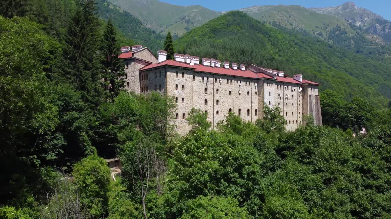 Drone ascending to reveal Rila Monastery with Rila mountains in the background