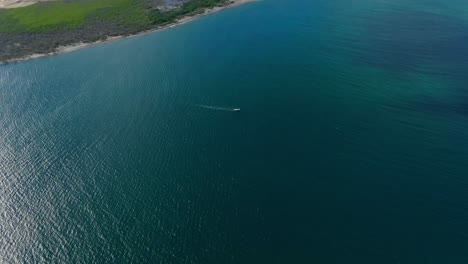 Aerial-view-Tilting-down-shot,-Scenic-view-of-Boat-floating-in-the-sea-of-La-Purisima-Baja-California-sur,-Mexico,-bright-light-reflecting-on-the-sea-in-the-background