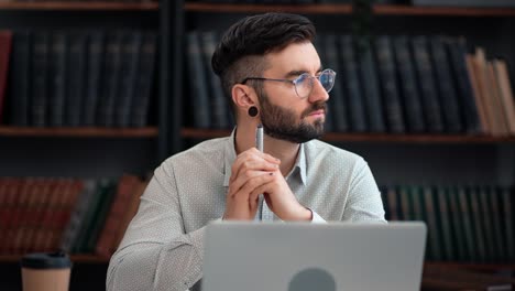 Pensive modern business man working use laptop thinking project analyzing at library cabinet