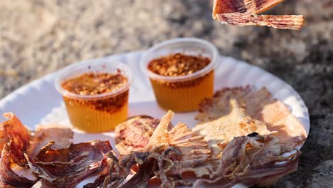 hand picking grilled squid with dipping sauce