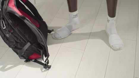close-up of person walking on light wooden floor in white socks and slippers. the image captures smooth movement, showcasing domestic comfort in a modern, minimalistic interior setting