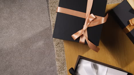 overhead shot of man putting gift wrapped present on table at home