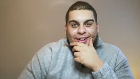 joven estudiante universitario tratando de contener la risa durante una videoconferencia en línea