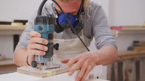 caucasian male surfboard maker wearing a face mask and making a surfboard