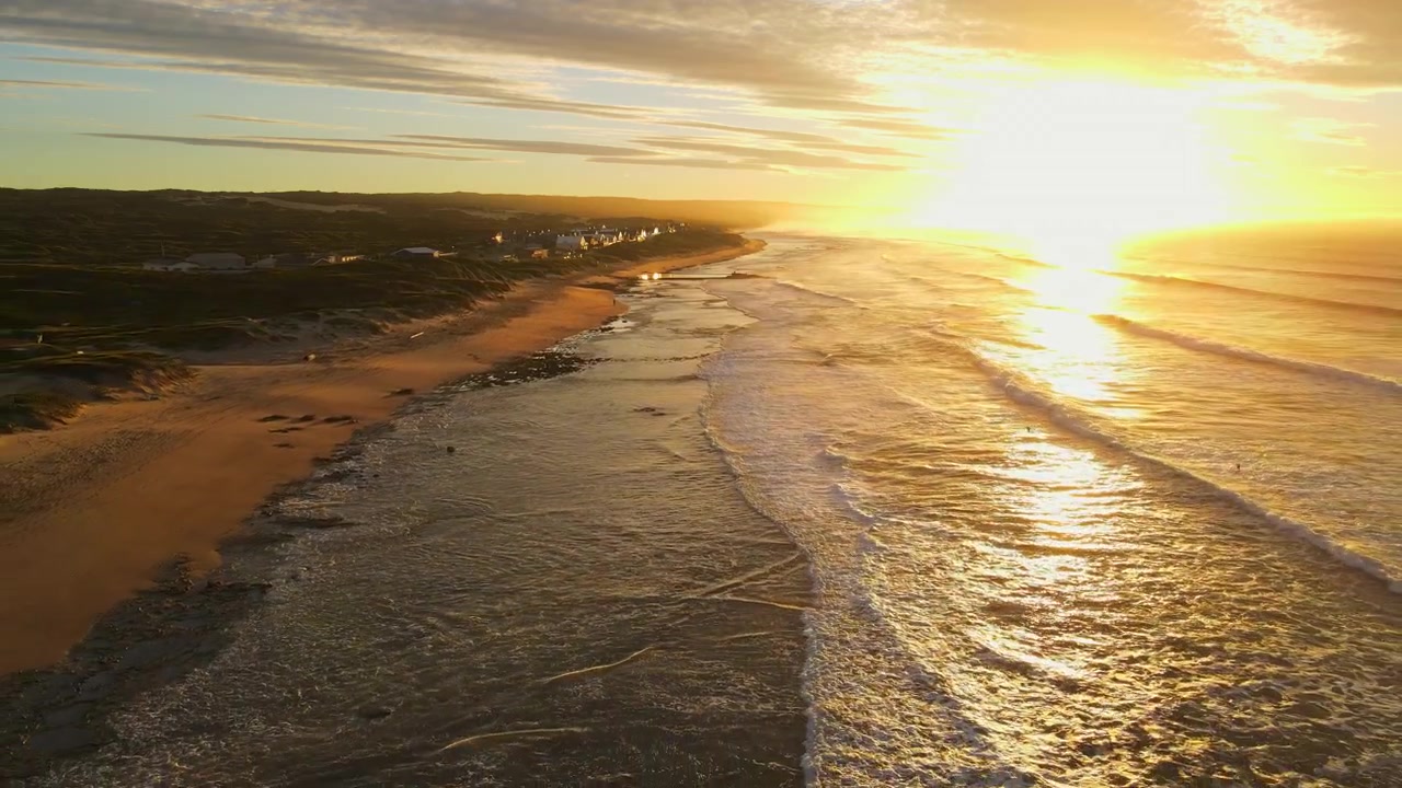 Naturskønt luftfoto ved solopgang over Witsand-stranden med brusende bølger, Garden Route.