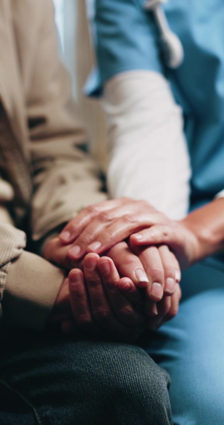 Infermiera che conforta un paziente anziano tenendogli le mani