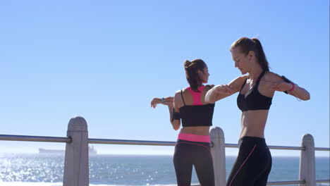 Two-athletic-friends-stretching-on-promenade-before-run