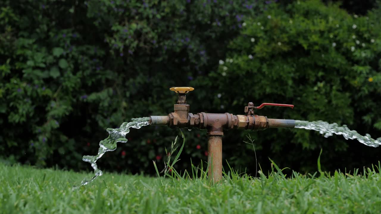 L'acqua spruzza da una doppia alimentazione idrica per la necessaria irrigazione di un giardino