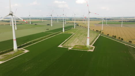 aerial view tilting over farmlands, revealing wind turbines at a eolic energy farm