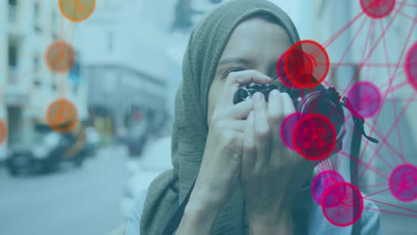 Animación-De-Una-Red-De-íconos-Rosados-Y-Naranjas-Conectados-Con-Una-Mujer-Con-Hijab-Tomando-Fotos
