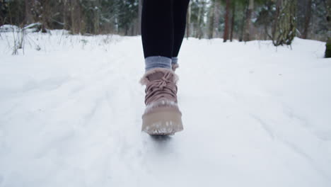 woman walking in snow-covered forest path