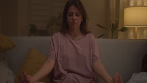 mujer meditando en un sofá en casa