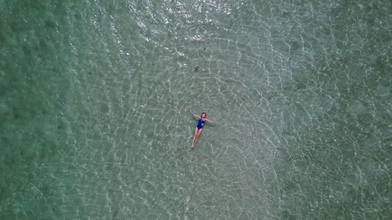mujer en traje de baño azul flotando en aguas cristalinas
