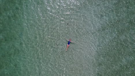 Frau-Im-Blauen-Badeanzug,-Der-In-Kristallklarem-Wasser-Schwimmt