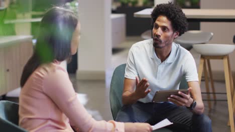 Video-of-focused-diverse-businesswoman-and-businessman-using-tablet-and-talking