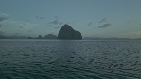 tropical seascape with large rock formation at dusk