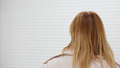 back view of lady with brown hair walking through bright laundromat corridor, casual jacket, hair moving, indoor blur of signage and carts, clean modern service setting, purposeful pace, calm mood