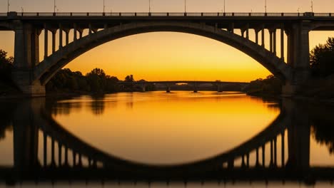 Stunning Sunset Reflection Over a Serene River Beneath a Majestic Bridge, Capturing the Tranquility of Nature's Evening Palette and Architectural Beauty