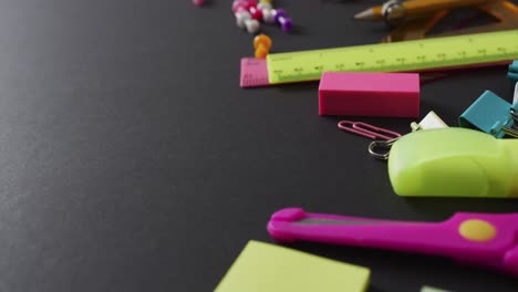 video van schoolbenodigdheden en notitieboeken, paperclips, pennen op zwarte achtergrond