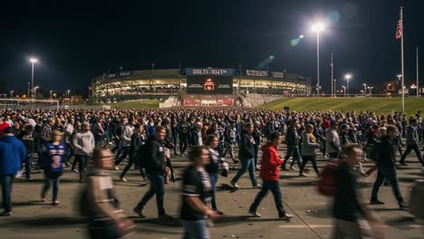 massive crowd leaving a stadium at night: a vibrant scene of fans exiting after an event, illuminated by stadium lights and the excitement in the air