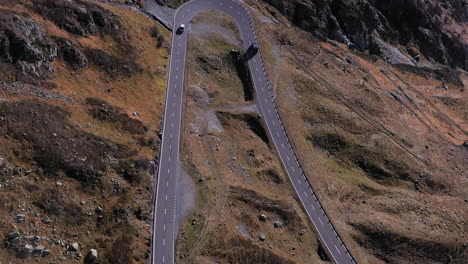 downward angle drone footage of a hairpin turn and vehicles on the susten pass in the swiss alps in switzerland