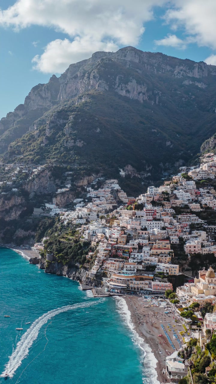 Vertical Drone Hyperlapse Over Positano with Dramatic Mountain Cliffs, Turquoise Mediterranean Water and Colorful Seaside Homes on Italy’s Amalfi Coast. Windy Conditions by the Seaside.