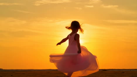 girl in dress twirling on beach at sunset