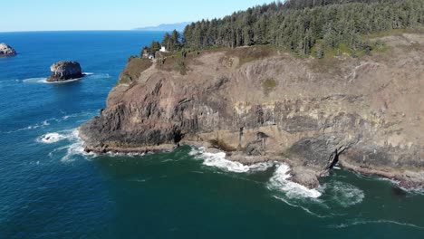 drone flies sideways looking at a lighthouse on a cliff near the ocean