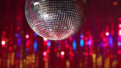 close up of mirrorball in night club or disco with flashing strobe lighting and sparkling lights in background