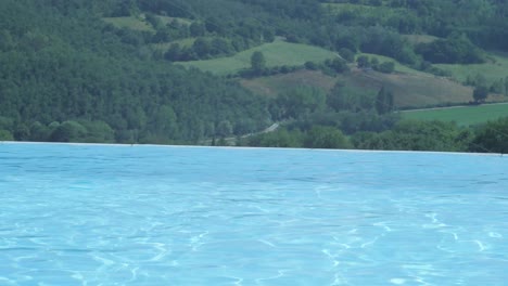 Luxurious-infinity-pool-on-the-hillside-of-remote-resort-with-on-the-background-a-leaving-vehicle