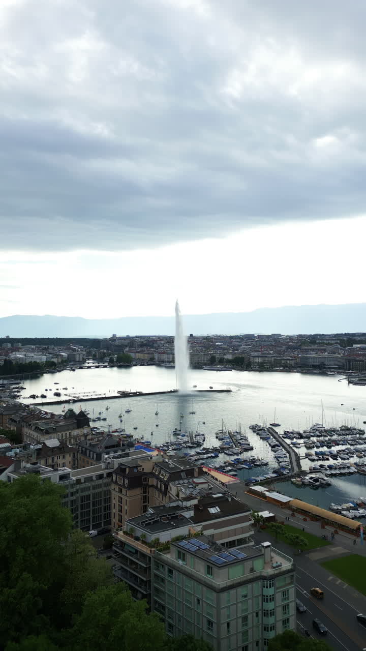 Vertical, aerial: water fountain of Geneva during the day (Rade of Geneva) in canton of Geneva, Switzerland, push in drone shot
