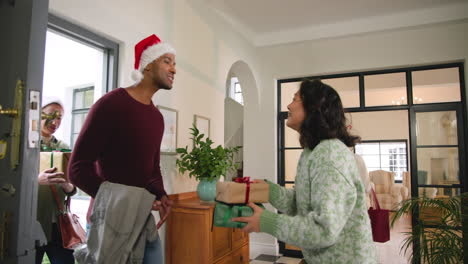diverse friends exchanging gifts and hugging at home during festive christmas celebration