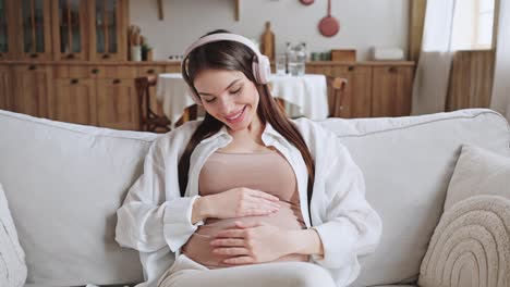 cheerful pregnant woman listens to music in headphones