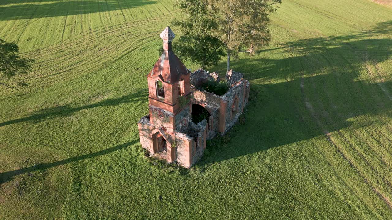 vuelo aéreo de drones sobre una ruina de iglesia perdida sin techo en estonia, europa - edificio de arenisca naranja que parece una pequeña iglesia ortodoxa o católica en un prado verde - vista de pájaro 2022
