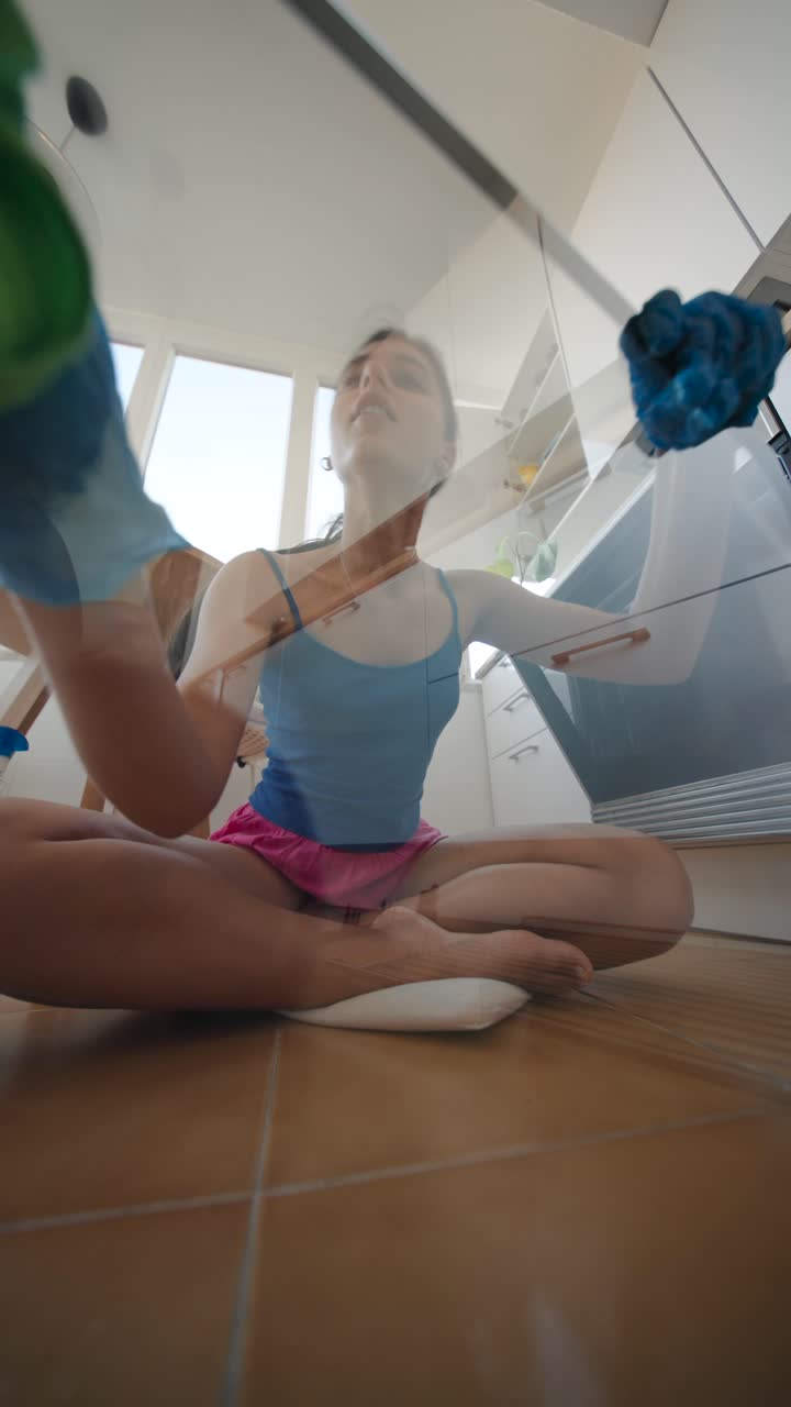 Woman cleaning glass cabinet in kitchen