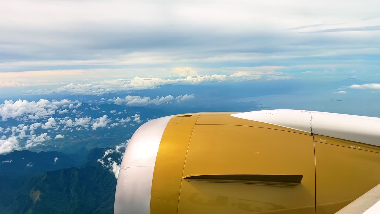 Beautiful view from airplane window with golden engine, mountain peaks, and drifting clouds, ideal for aviation, travel, and exploration projects
