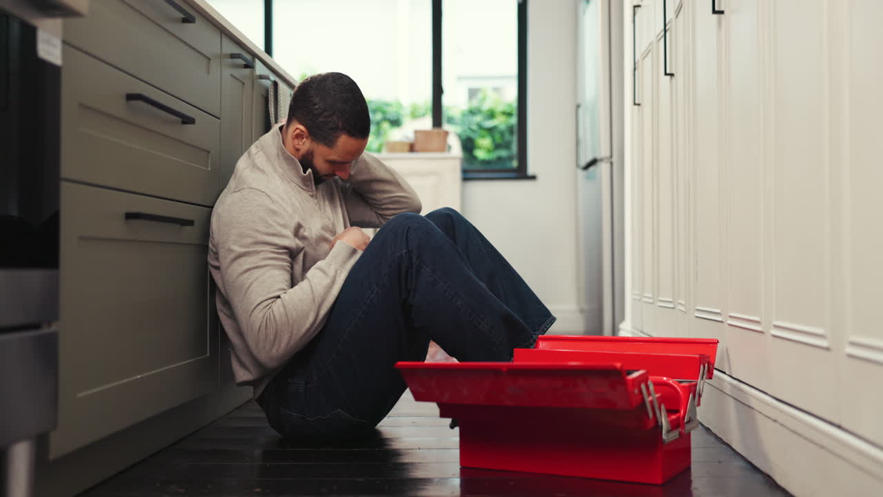 Worried man sitting near a toolbox in the kitchen