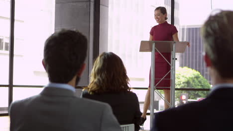 mujer presentando un seminario de negocios, la audiencia aplaudiendo, filmado en r3d