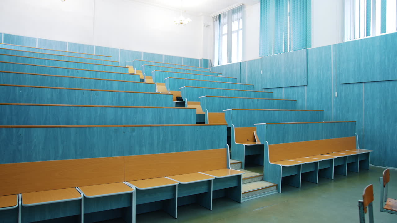 Modern auditorium with wooden desks without people. Large meeting hall with empty desks. Nobody in lecture hall in the university during quarantine.